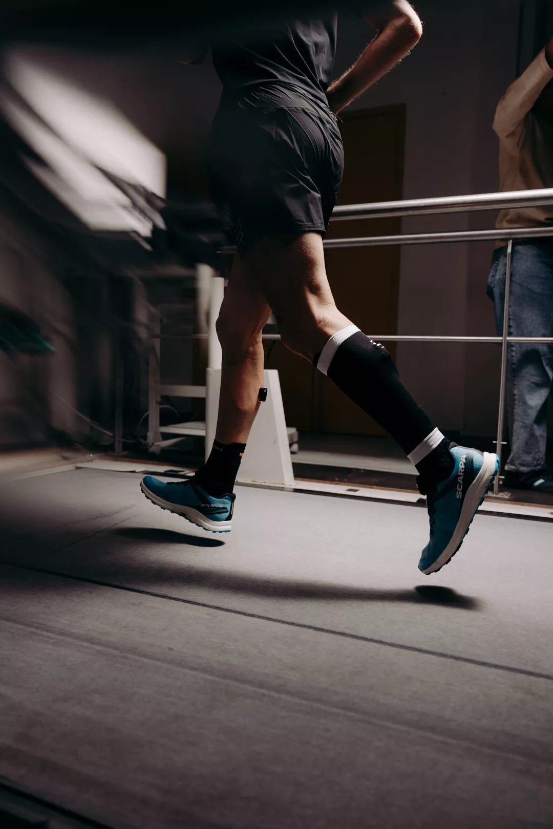 Runner's legs in compression socks on a treadmill in the Compressport Lab