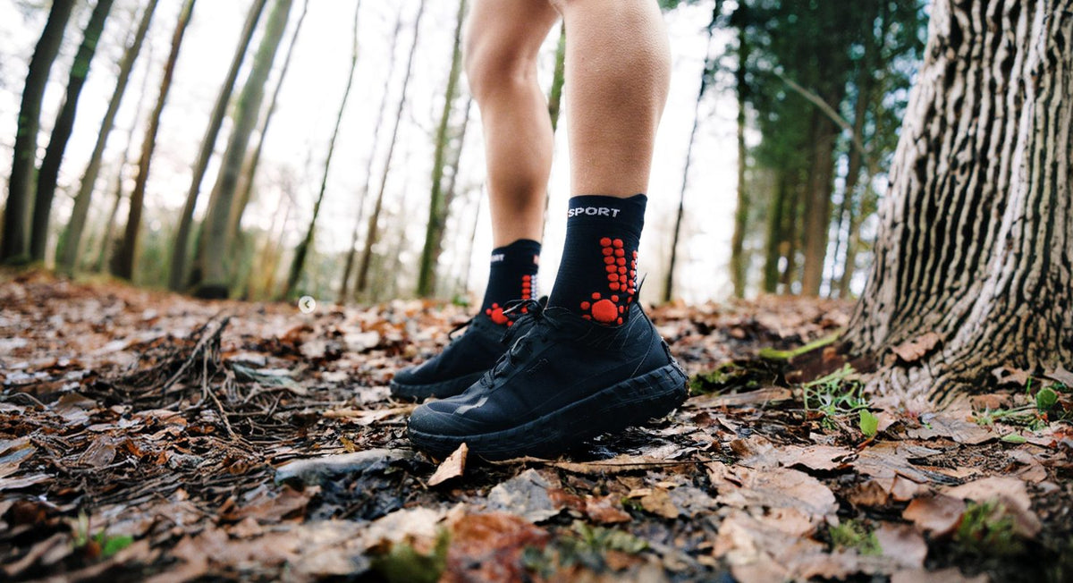 Runner on a forest trail wearing Compressport socks